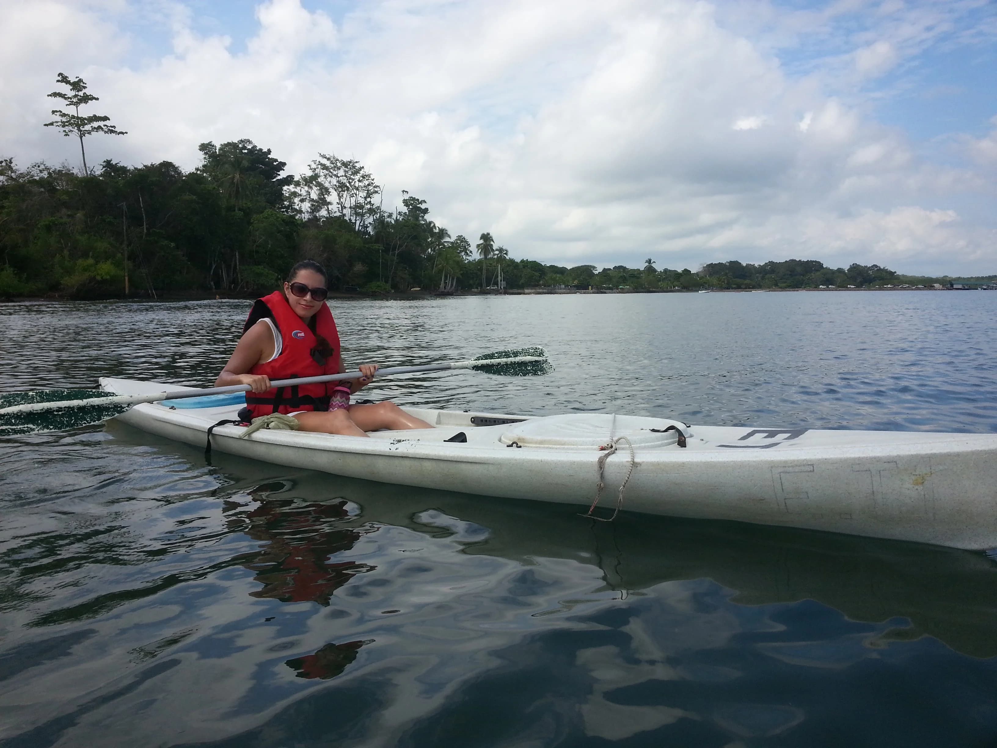 Kayaks resting on a calm river bank at the edge of a dense mangrove forest.