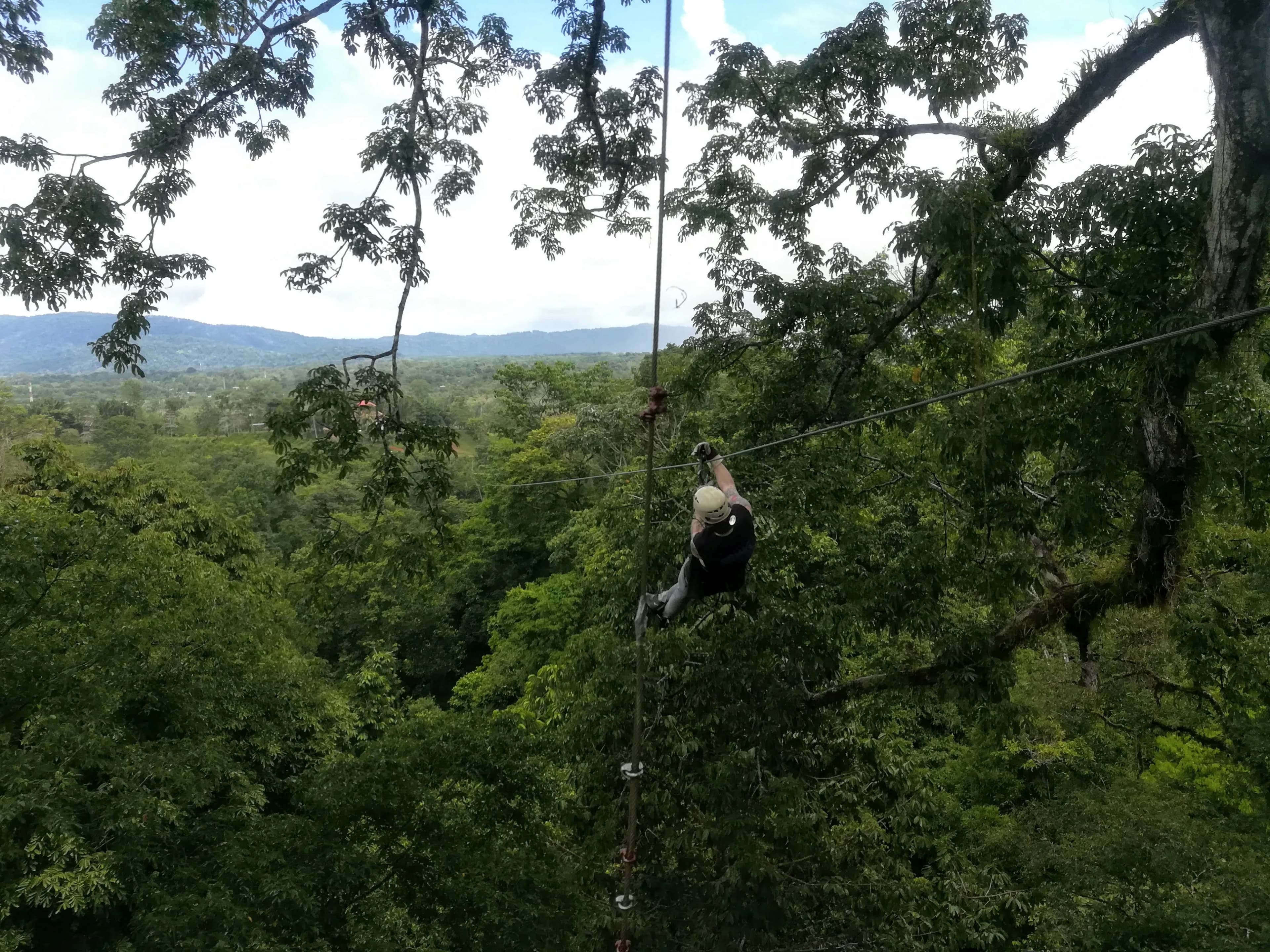 A person ziplining high above the jungle canopy.
